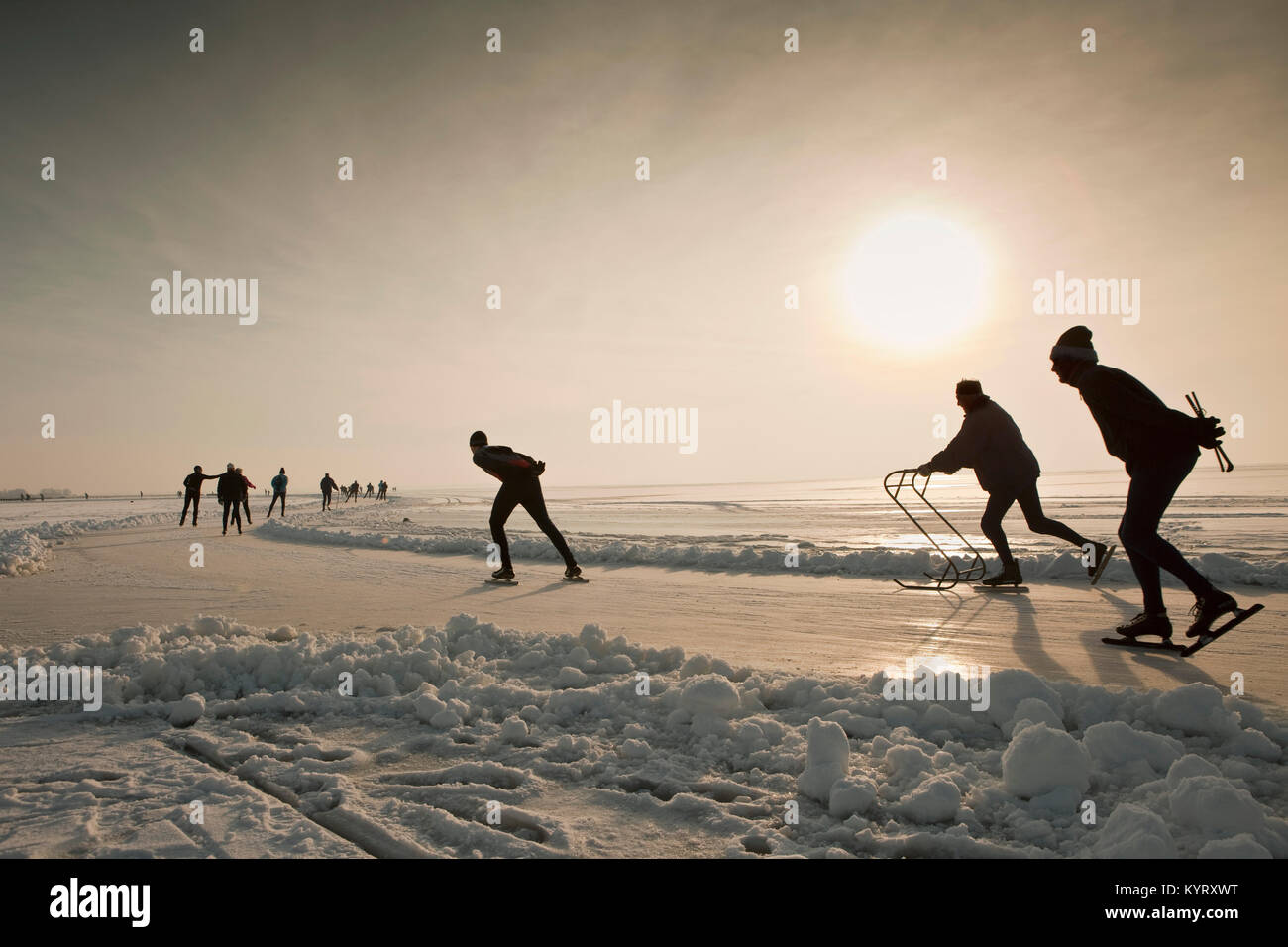 Die Niederlande, Hindeloopen, Eislaufen am See namens IJsselmeer bei Sonnenuntergang. Winter. Stockfoto
