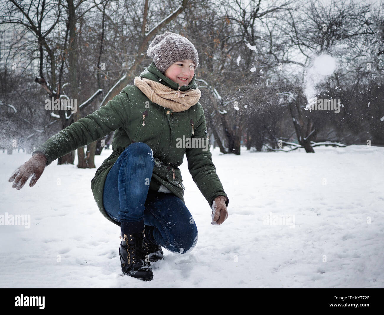 Glückliches Mädchen wirft einen Schneeball. Winter im Freien Stockfoto