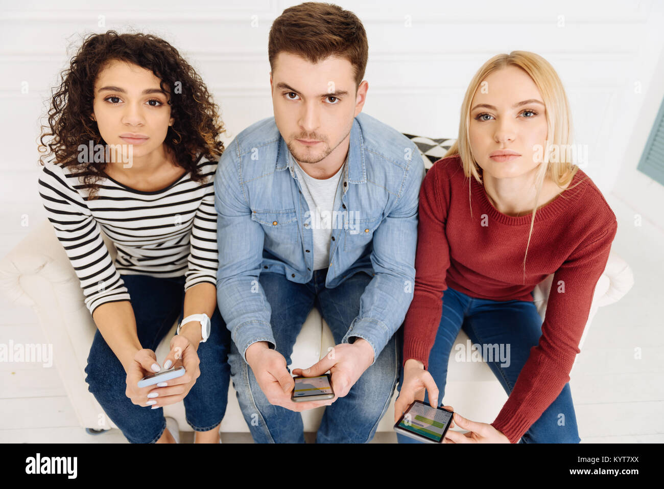 Stattliche männliche Person sitzt zwischen seinen Freunden Stockfoto