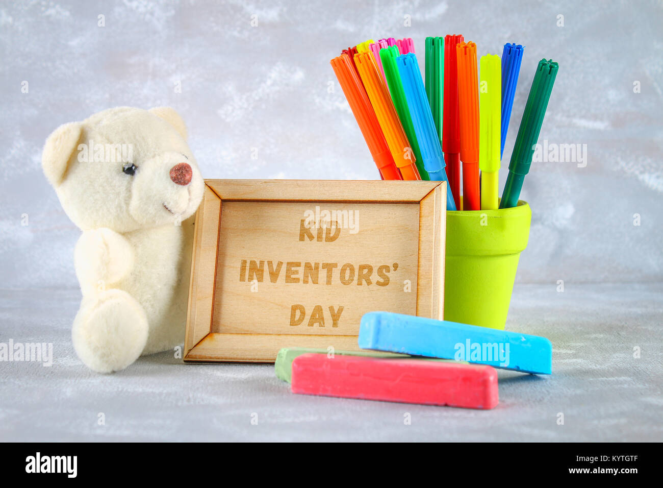 Teddybär, Marker, Plakette und Zeichnungen von Erfindungen für Kinder - Eis  am Stiel, Ohrenschützer, Rechner auf einem grauen Hintergrund. Text-Kid  Erfinder' Tag Stockfotografie - Alamy