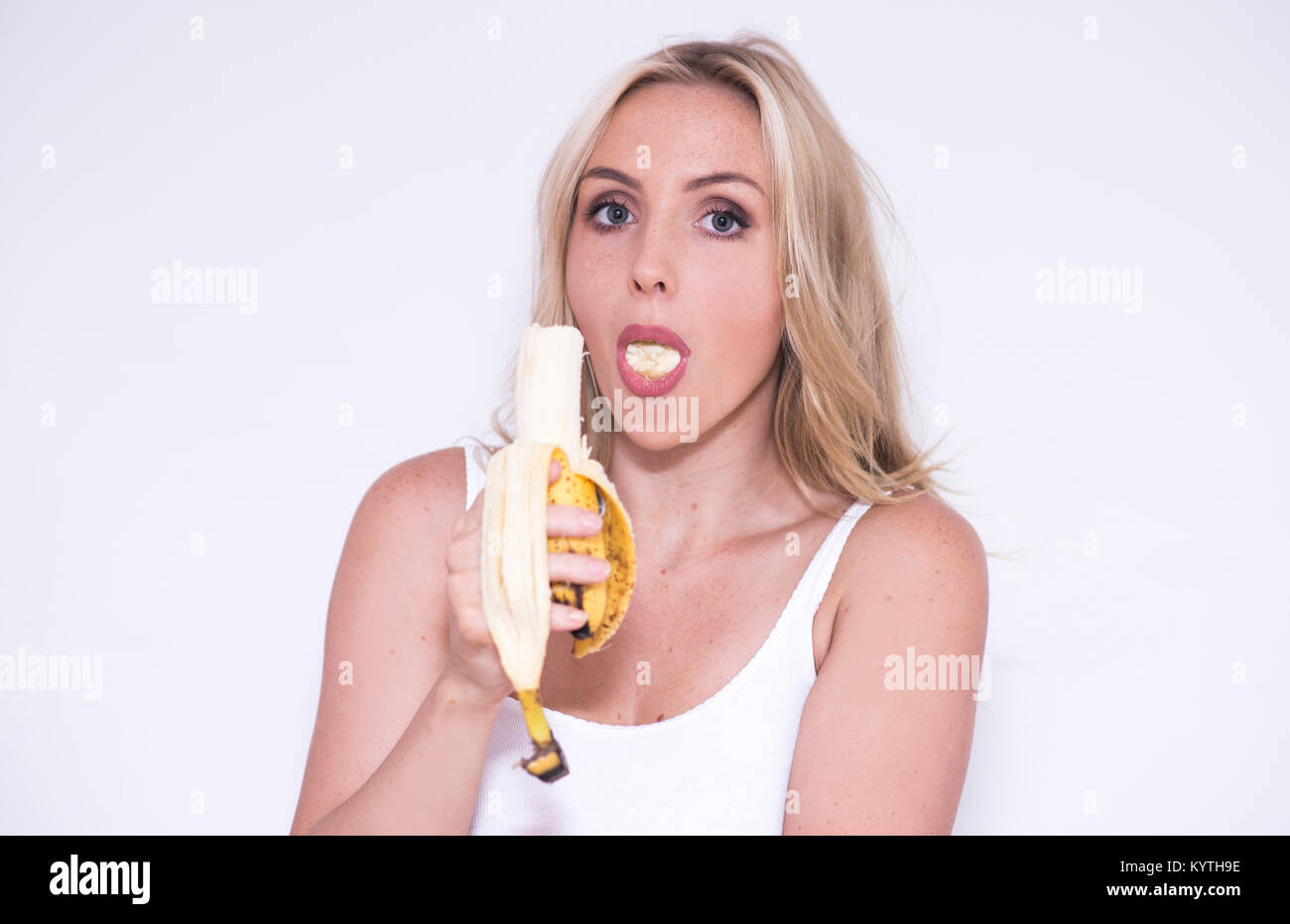 Hübsche blonde Frau isst eine Banane Stockfotografie - Alamy