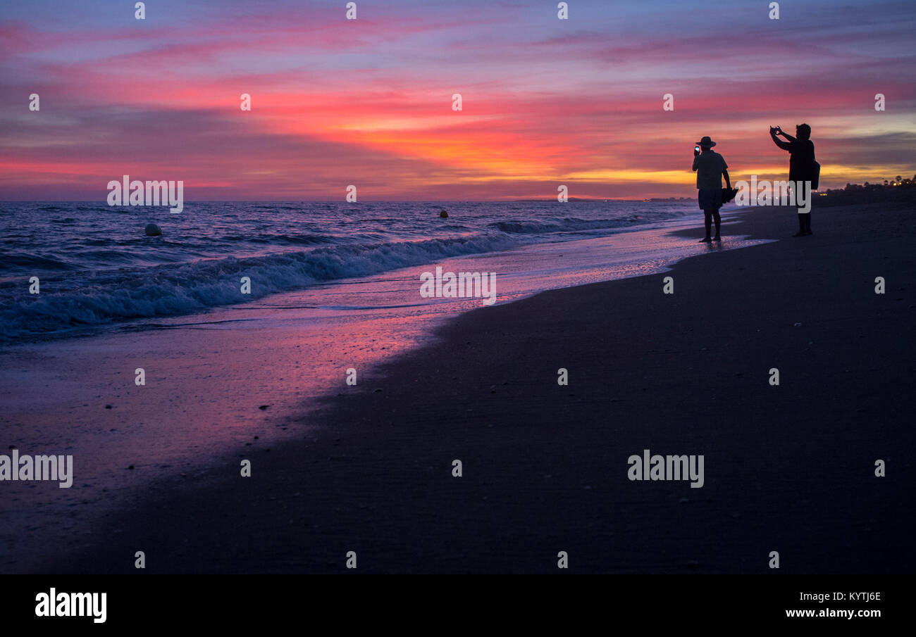 Elder touristische paar Fotos am Strand von Islantilla während den herrlichen Sonnenuntergang. Huelva, Spanien Stockfoto