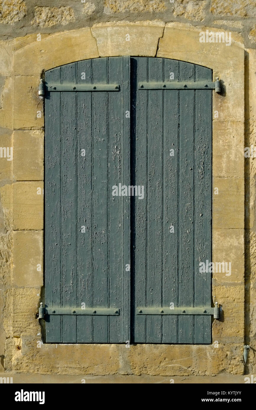 Abblätternde Farbe auf einem alten Fensterläden in einem hübsch restaurierte Steinmauer gesetzt Stockfoto