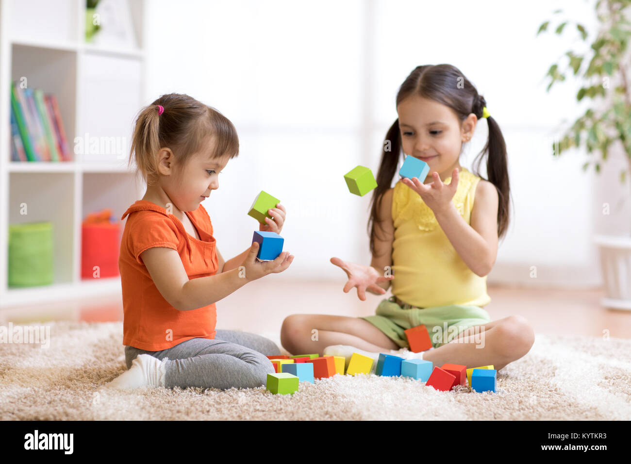 Süße Kinder spielen beim Sitzen auf dem Teppich zu Hause oder im Kindergarten Stockfoto