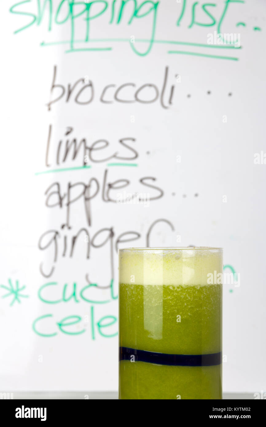 Ein grünes Obst und Gemüse Smoothie in ein Glas. Ein whiteboard Einkaufsliste im Hintergrund. Stockfoto