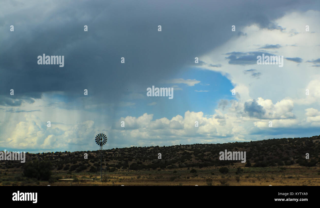 Dramatische Himmel mit Wolken und Regen am Horizont über der Wüste im Südwesten der USA mit Mühle Stockfoto