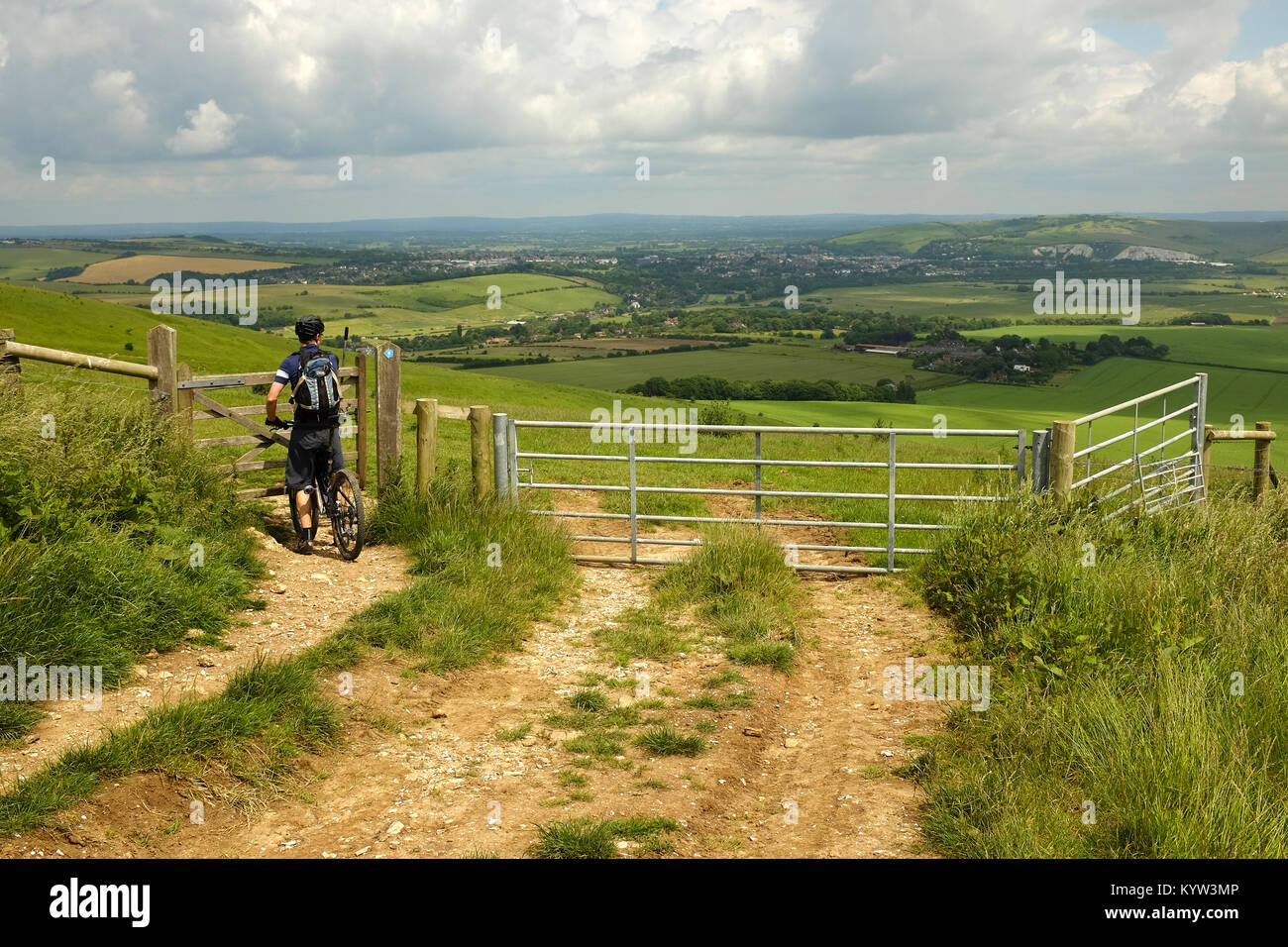 Eine männliche Radfahrer auf dem Mountainbike zu einem Tor auf der South Downs Way Wanderweg in der Nähe von Lewes, East Sussex. Stockfoto