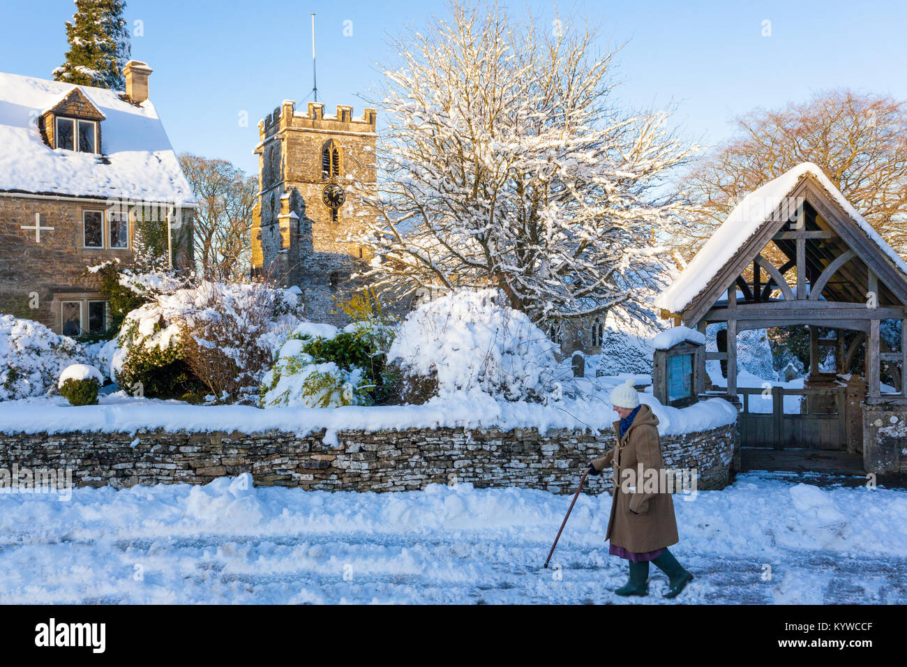 Nach Hause in den späten Nachmittag an einem verschneiten Tag vorbei an der Kirche des Hl. Andreas in der Cotswold Dorf Miserden, Gloucestershire, Großbritannien Stockfoto