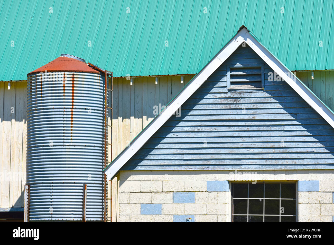 Farm Architektur hautnah mit einem kleinen Silo. Das Dach scheint neu zu sein, während das Gebäude in einem schlechten Zustand ist. Stockfoto