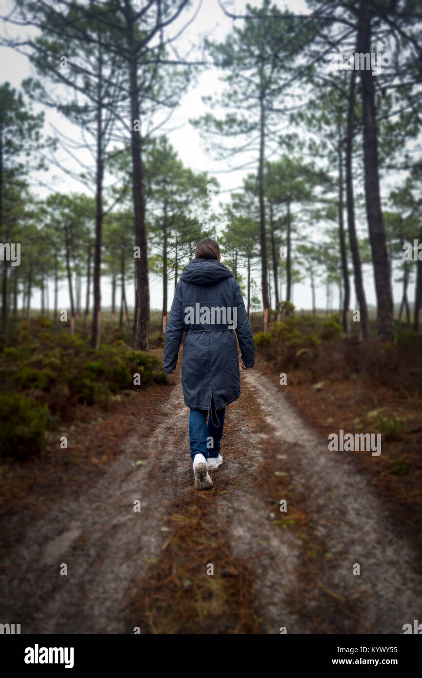 Frau gehen durch einen Wald im Nebel und Hochnebel. Stockfoto