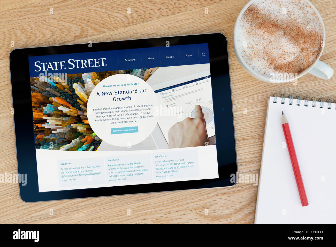 Die State Street Corporation Website auf einem iPad Tablet, auf einen hölzernen Tisch neben einem Notizblock, Bleistift und Tasse Kaffee (nur redaktionell) Stockfoto
