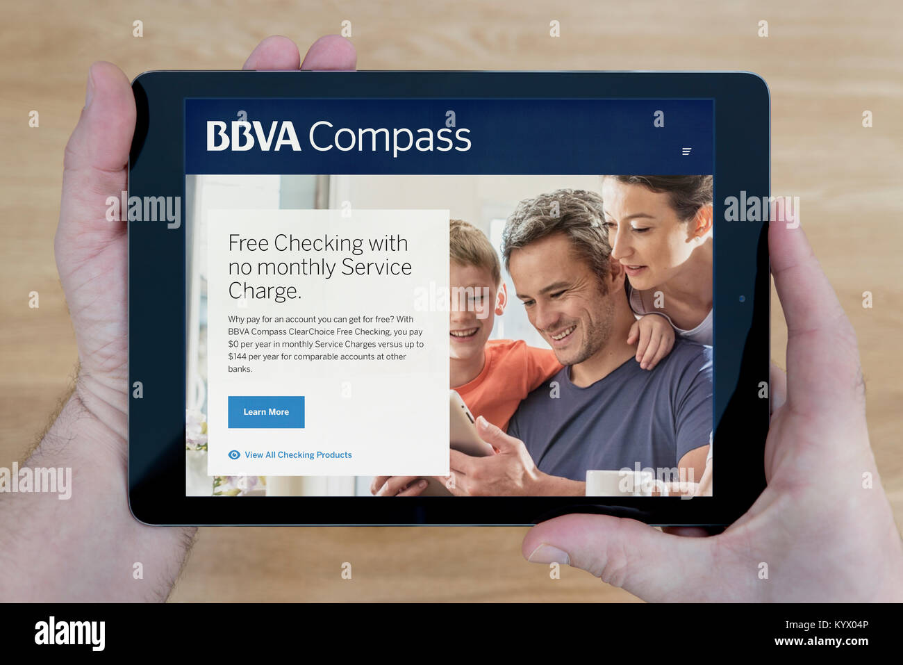 Ein Mann schaut auf die BBVA Compass Website auf seinem iPad tablet device, mit einem hölzernen Tischplatte Hintergrund (nur redaktionelle Nutzung) Stockfoto