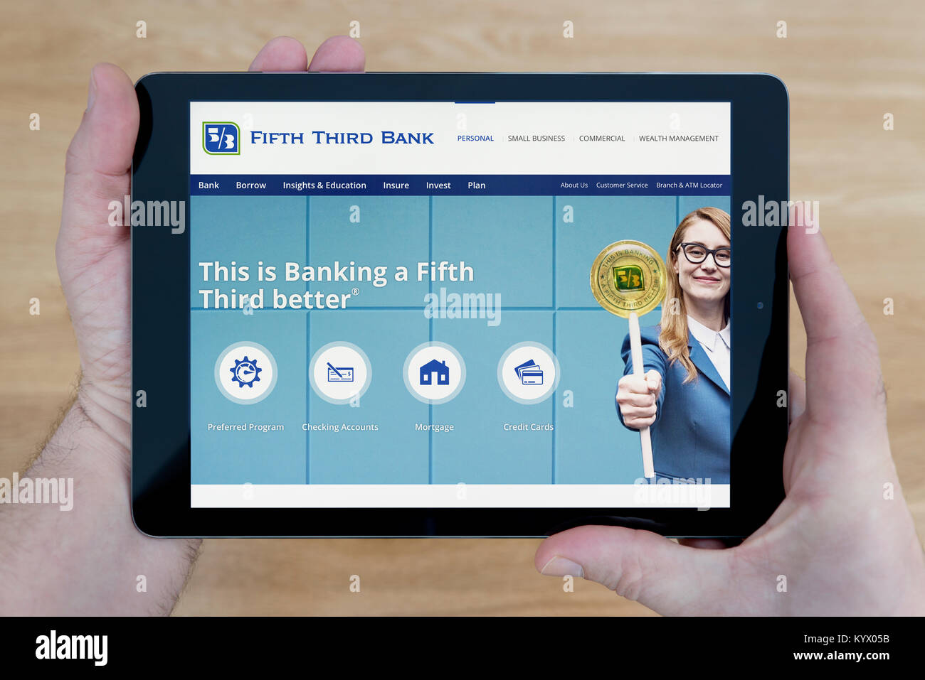 Ein Mann schaut auf die Fifth Third Bank Website auf seinem iPad tablet device, mit einem hölzernen Tischplatte Hintergrund (nur redaktionelle Nutzung) Stockfoto