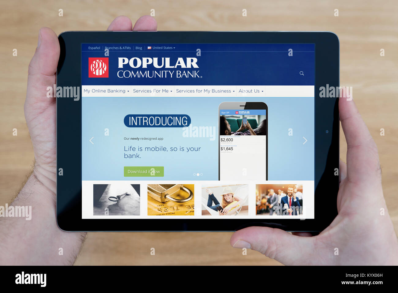 Ein Mann schaut auf der beliebten Community Bank Website auf seinem iPad tablet device, mit einem hölzernen Tischplatte Hintergrund (nur redaktionelle Nutzung) Stockfoto