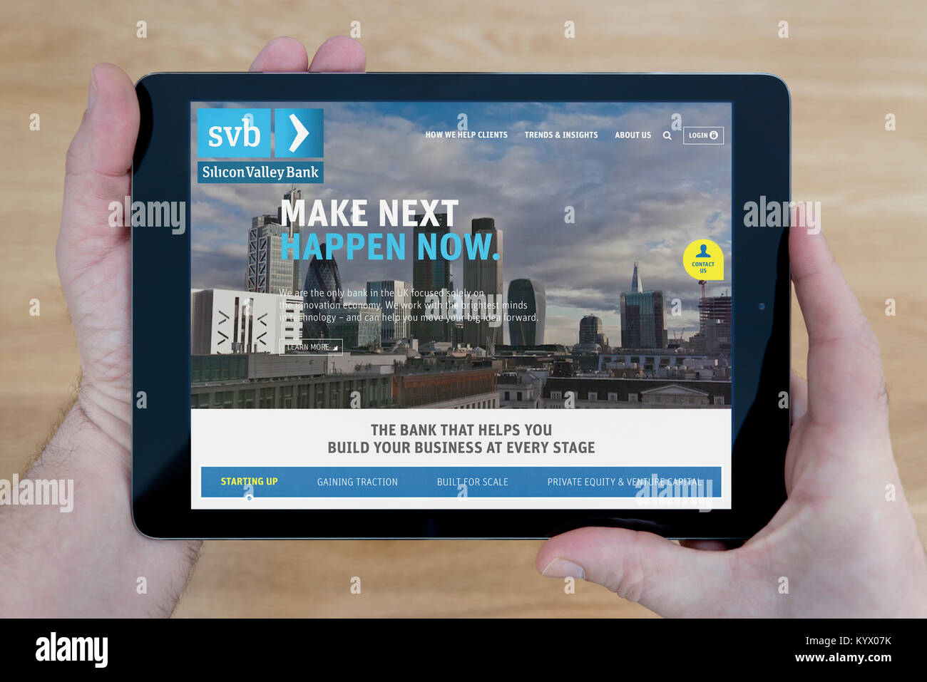 Ein Mann schaut auf der Silicon Valley Bank (SVB) Website auf seinem iPad tablet device, mit einem hölzernen Tischplatte Hintergrund (nur redaktionelle Nutzung) Stockfoto
