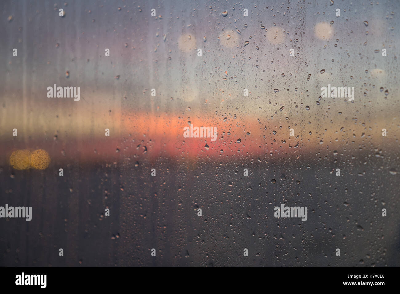 Regentropfen auf außerhalb des Geistes von Tasmanien Kabinenfenster bei Sonnenuntergang mit Clearing blue sky orange Wolken und Reflexion von Dim Deckenleuchte der Innenbeleuchtung. Stockfoto