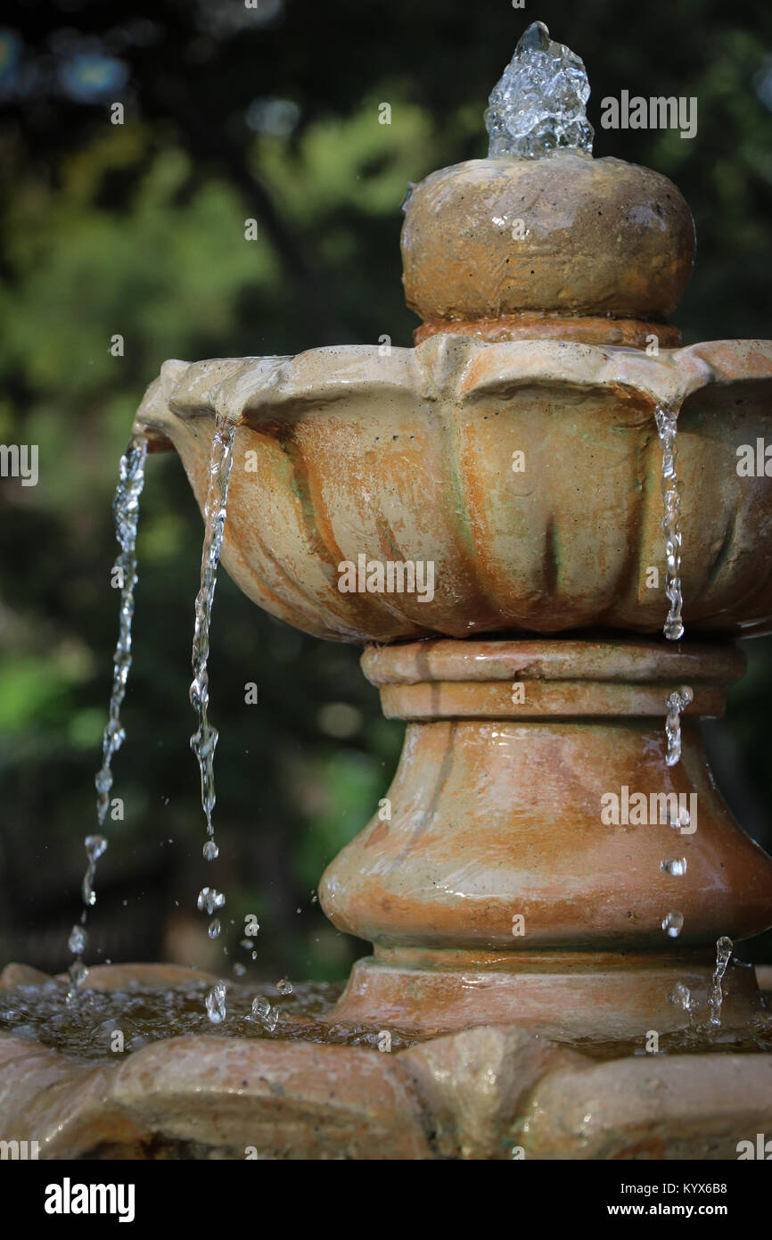 Nahaufnahme der obersten Stufe einer Garten Brunnen, mit Wasser sprudelnde von oben in ein Becken, dann fließt wie kleine Bäche in einen unteren Becken. Stockfoto