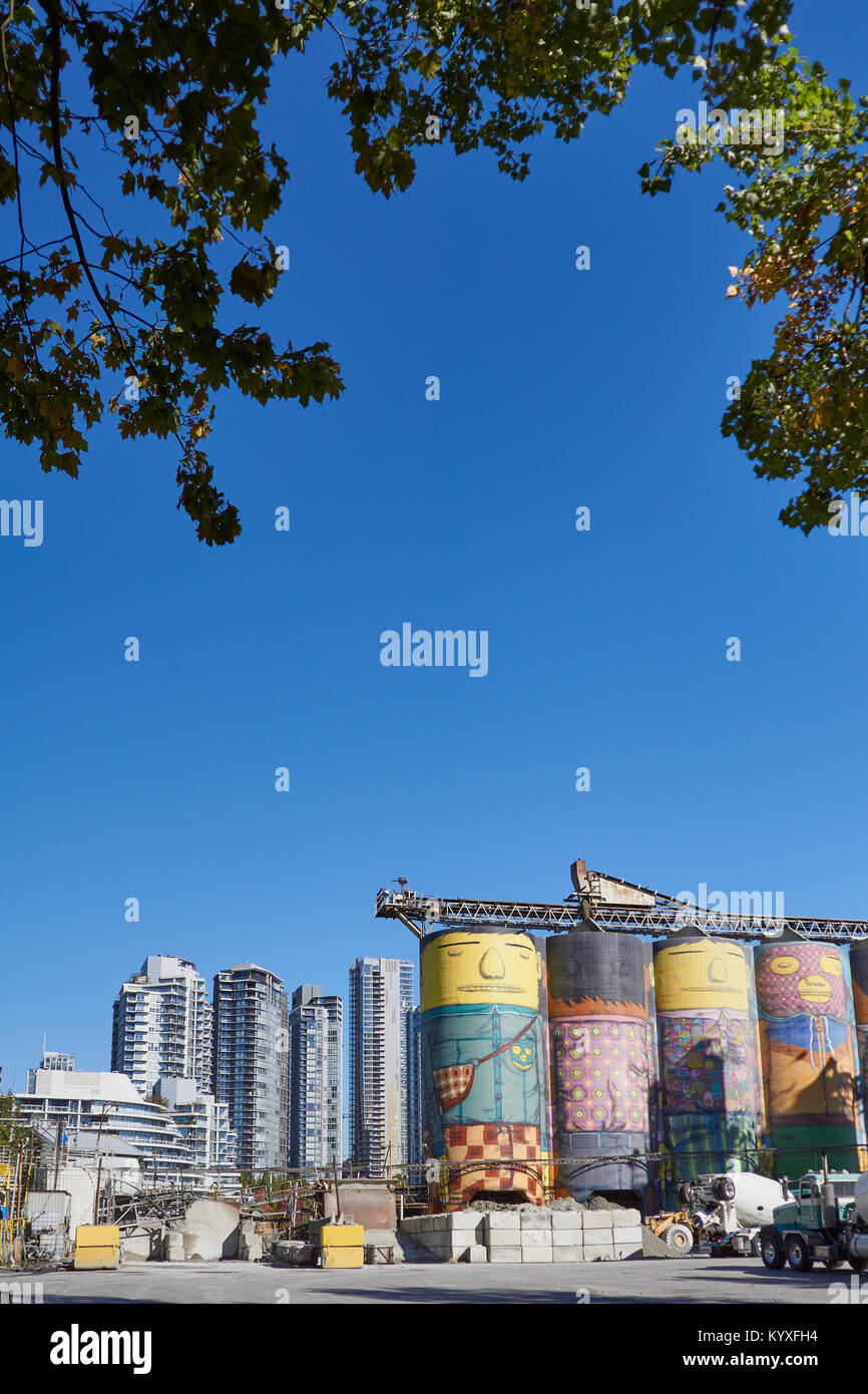 Riesige kunst Silos von Street Artists' OSGEMEOS' (die Pandolfo Zwillinge) für die Vancouver Biennale, auf einen konkreten Arbeitsplatz mit der Skyline hinter Stockfoto