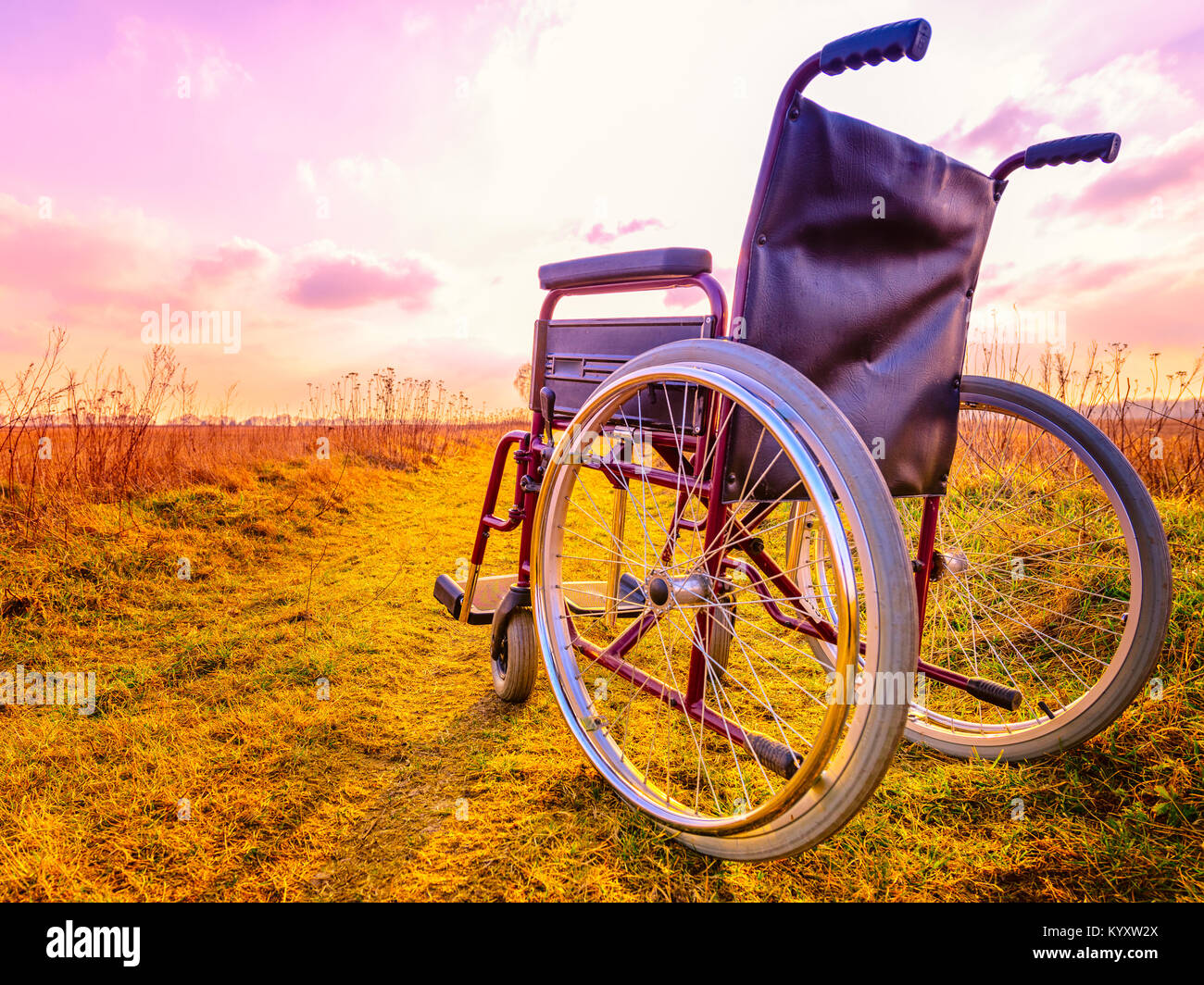 Leeren Rollstuhl auf der Wiese bei Sonnenuntergang. Wunder Konzept. Geheilt Person angehoben und ging weg Stockfoto