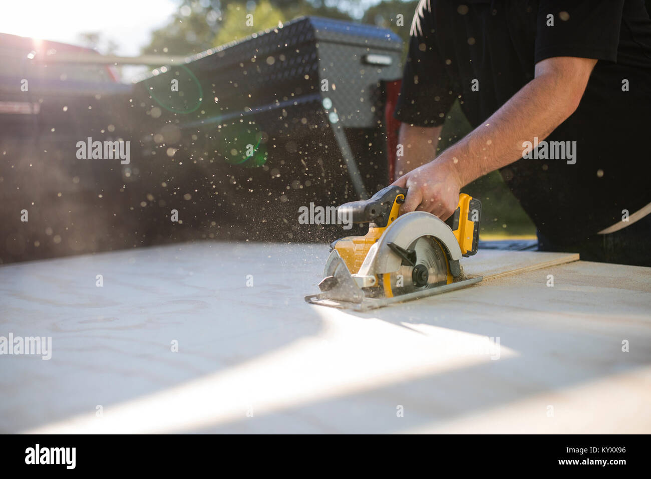 Mittelteil des Menschen mittels elektrischer sah beim Sägen Holzbrett im Hof Stockfoto