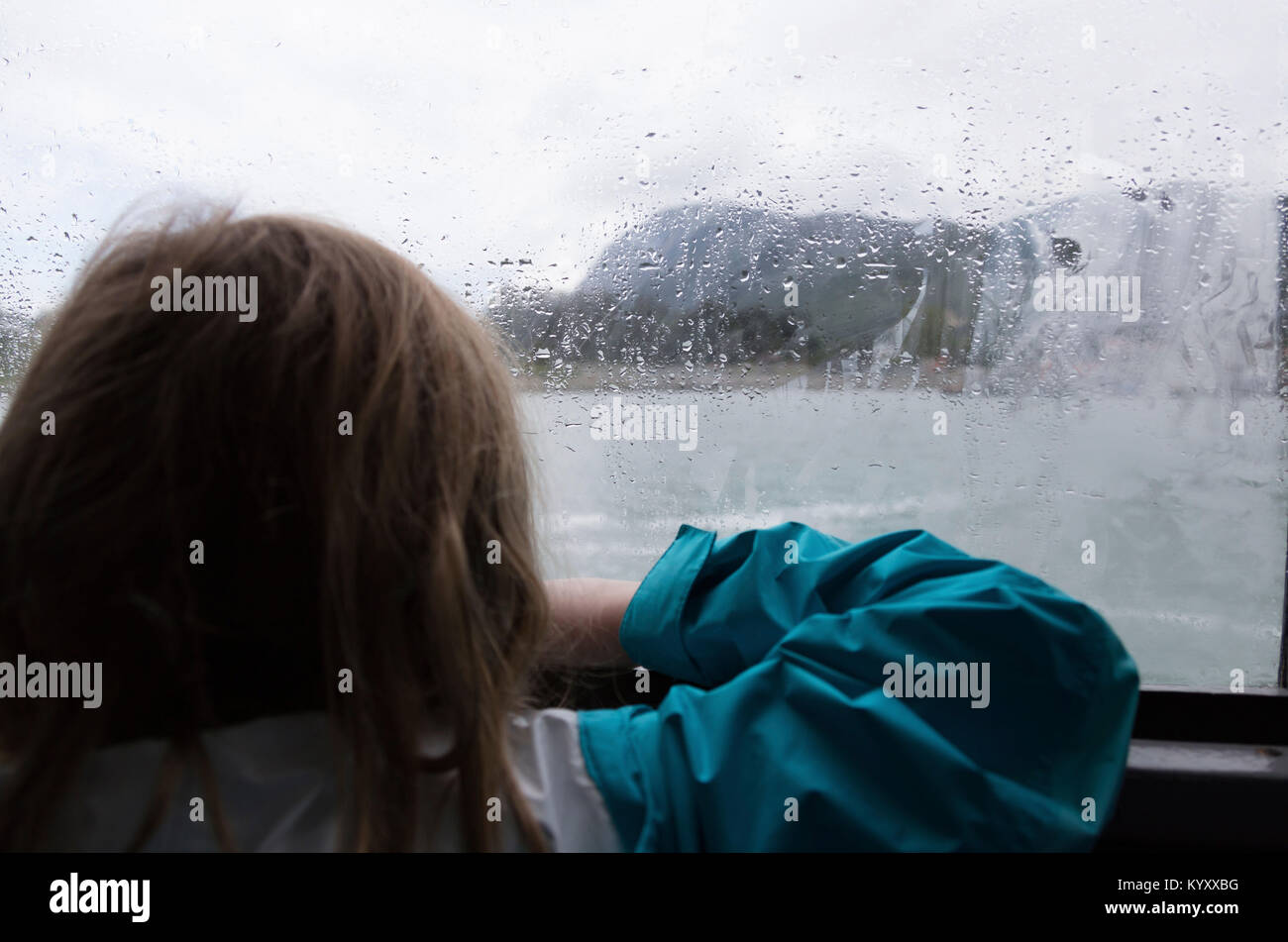 Ansicht der Rückseite des Mädchens auf der Suche durch nasses Fenster Stockfoto