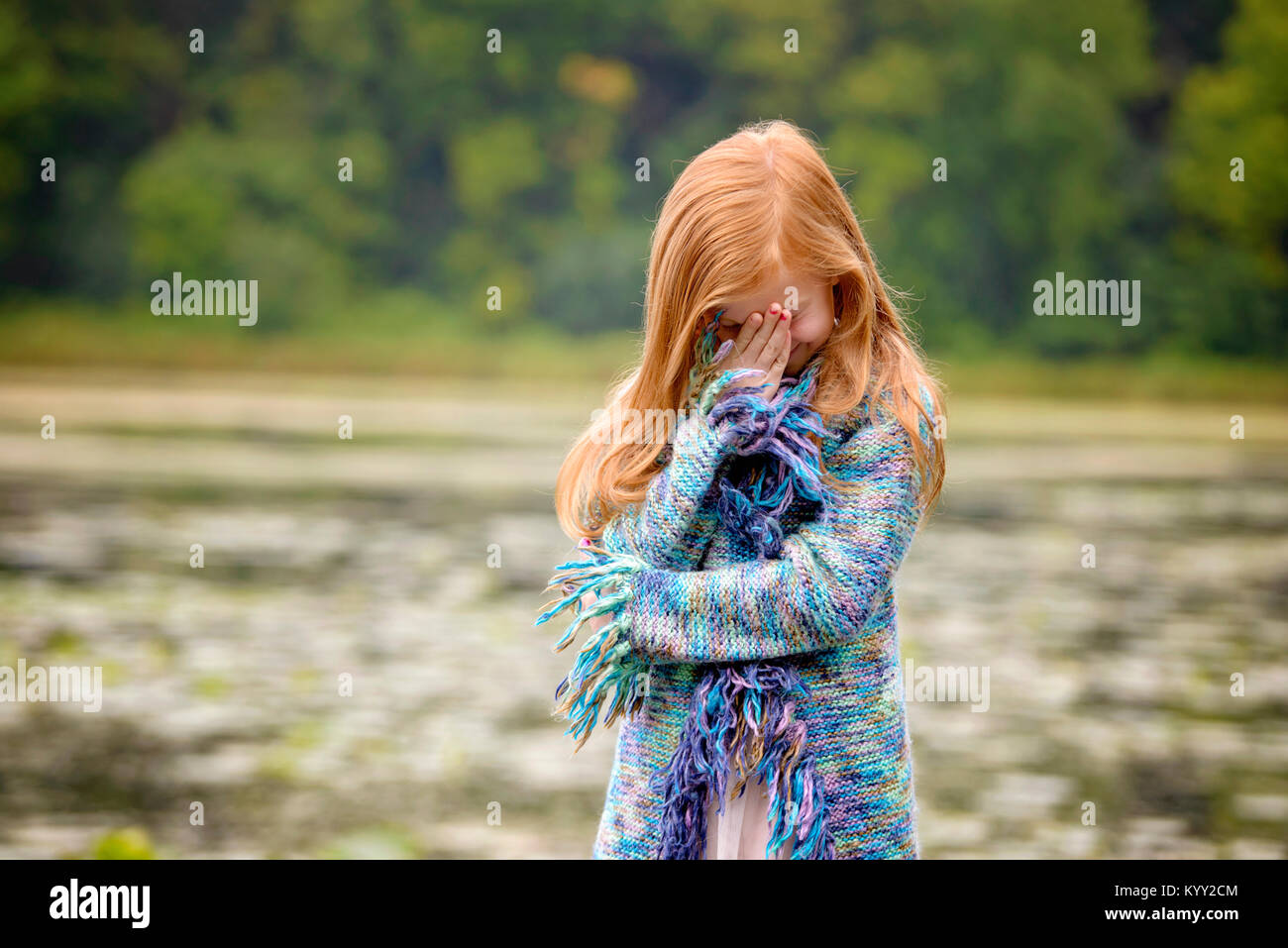 Mädchen versteckt sich das Gesicht mit der Hand im Stehen gegen See Stockfoto