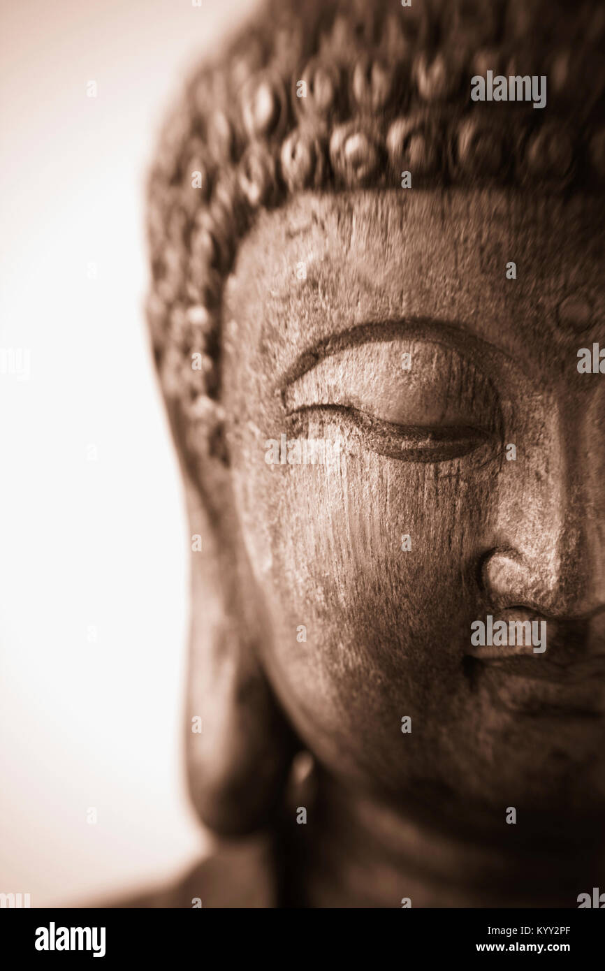 Dies ist eine Nahaufnahme eines antiken Holz schnitzen einer Skulptur von Buddha mit Fokus auf die niedergeschlagenen Augen. Das Bild wurde mit einem Lensbaby genommen Stockfoto