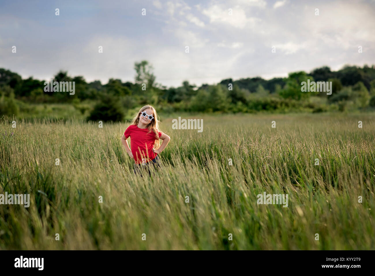 Portrait von zuversichtlich Mädchen mit Stern Sonnenbrille beim stehen inmitten von Feld Stockfoto
