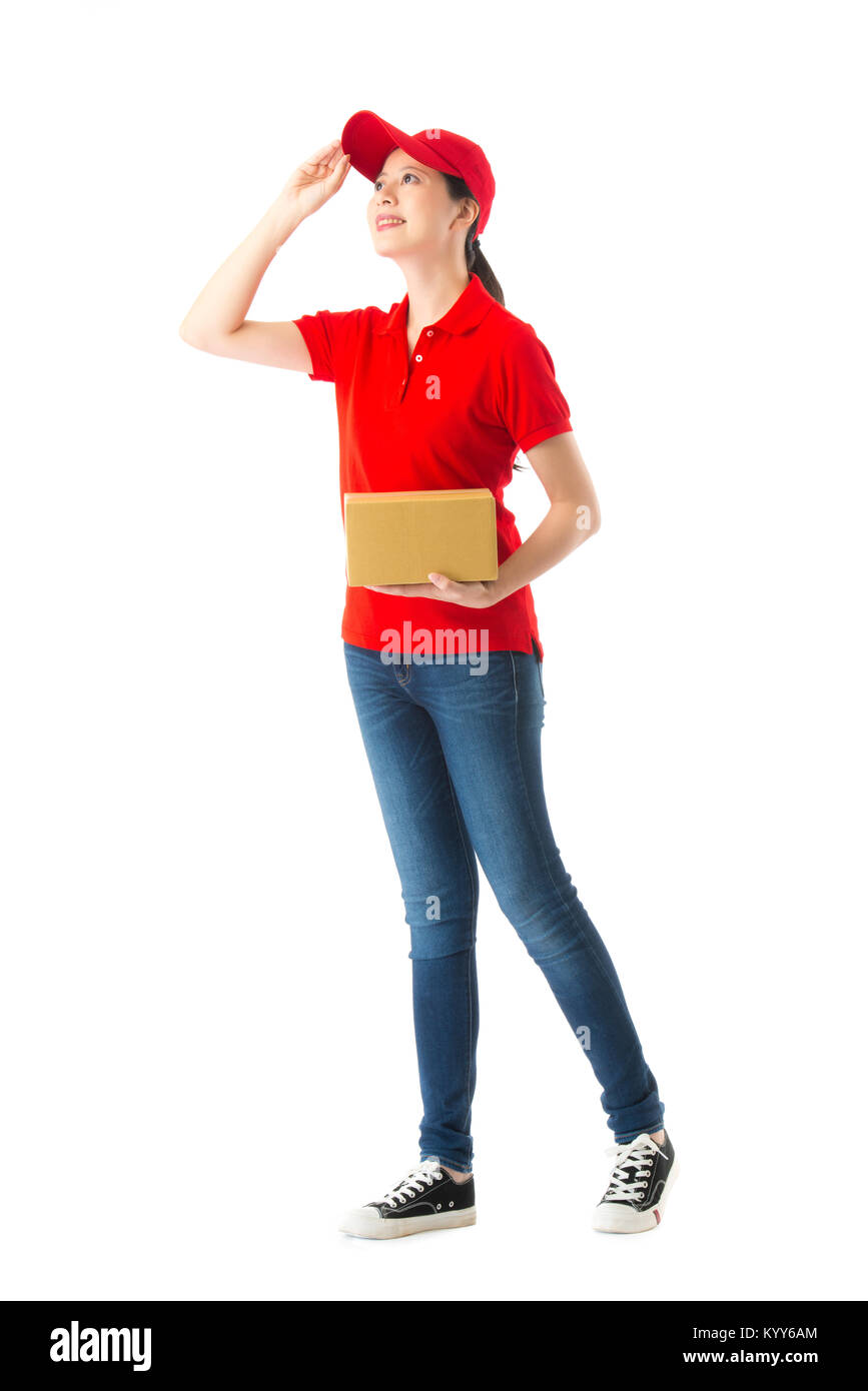 Volle Länge Foto der hübschen weiblichen Delivery officer Holding Box suchen Abstand suche Paket richtige Adresse auf weißem Hintergrund lächelnd. Stockfoto