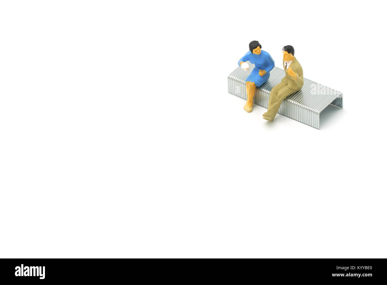 Miniatur 2 Leute sitzen auf Heftklammern auf weißem Hintergrund platziert. Sitzung oder Diskussion als Hintergrund Business Konzept mit Kopie Räume für Ihre tex Stockfoto