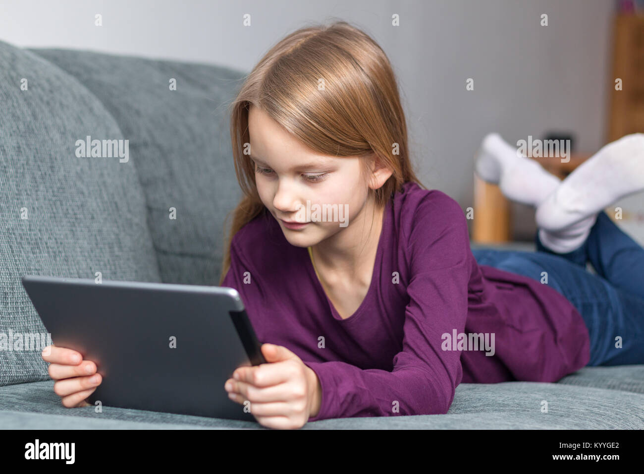 Ein Mädchen liegt auf dem Sofa mit einem Tablet-PC in Ihren Händen Stockfoto