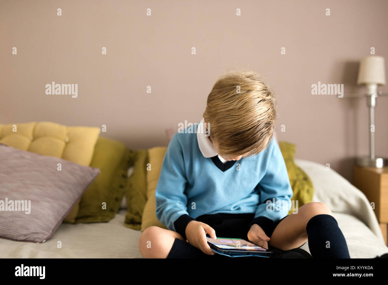 Junge mit digitalen Tablet im Schlafzimmer im Schlafzimmer Stockfoto