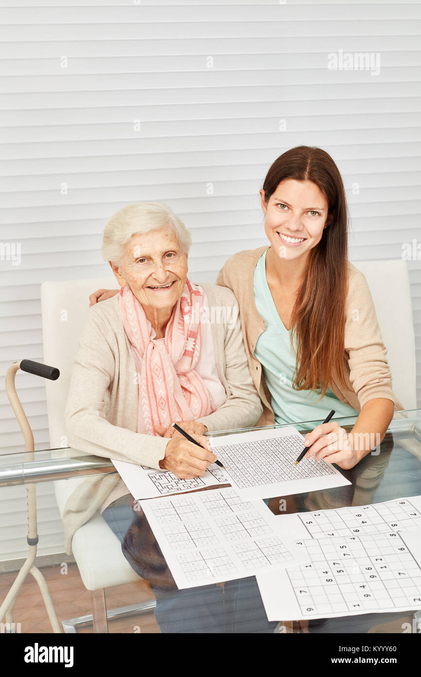Senior als glückliche Oma und Mädchen als Enkel Sudoku Puzzle lösen Stockfoto