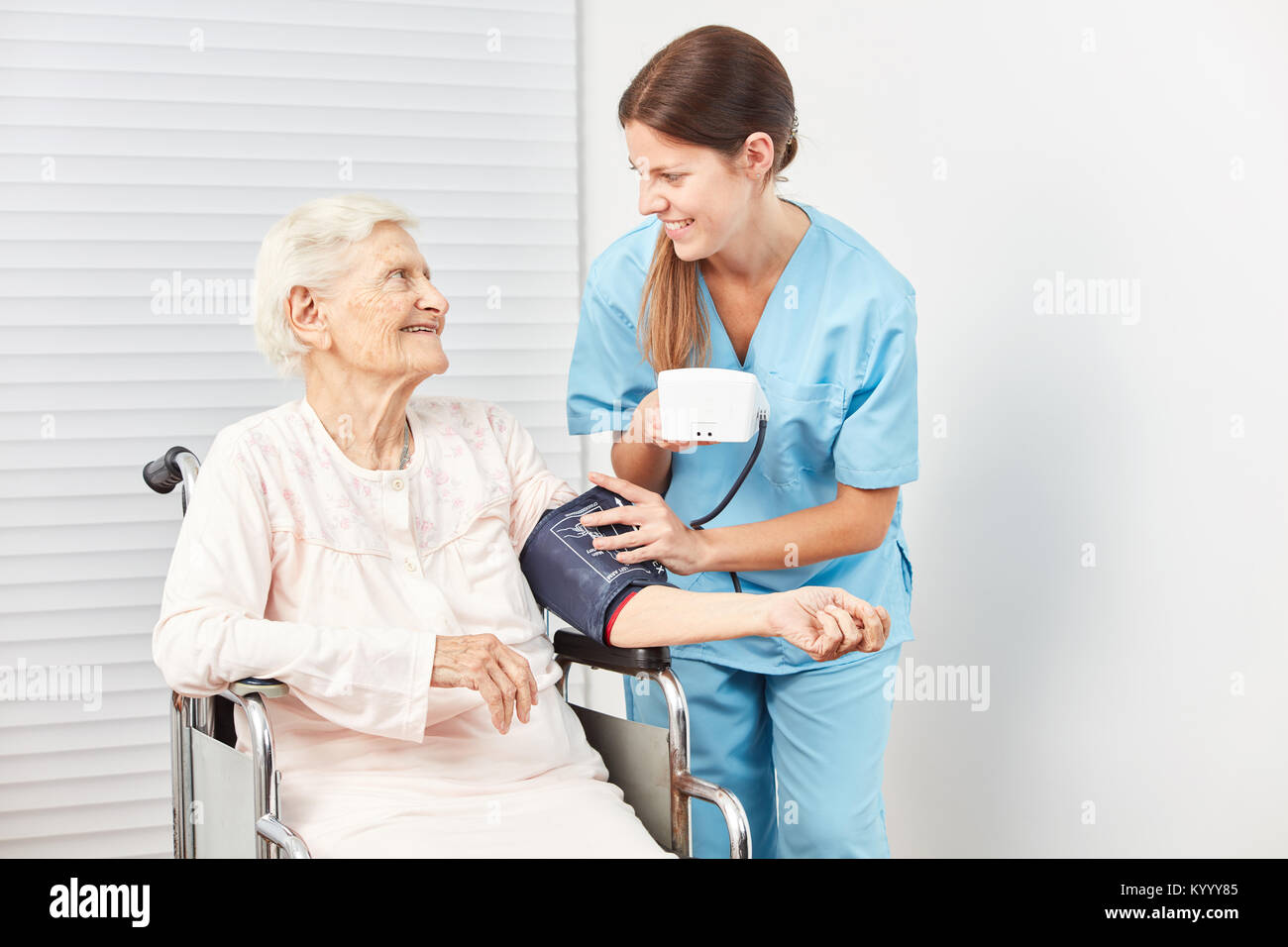 Junge Betreuer misst den Blutdruck eines älteren ältere Frau als Patient Stockfoto