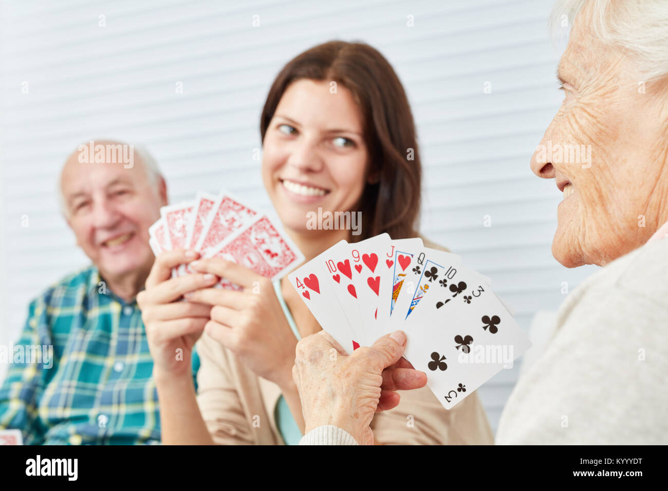 Enkelin spielt Karten zusammen mit Großeltern im Pflegeheim oder zu Hause Stockfoto