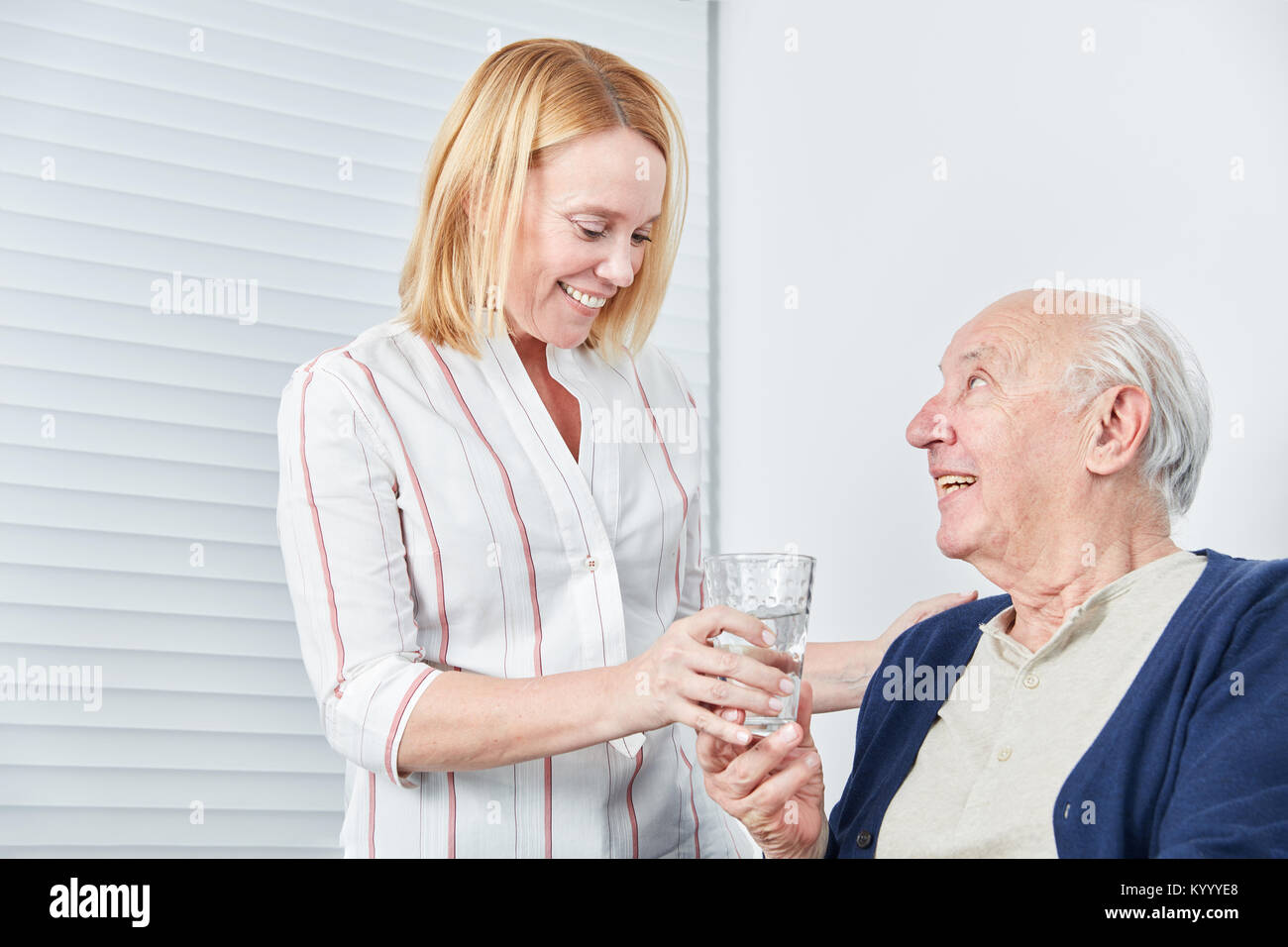 Junge Frau gibt Senior ein Glas Wasser, die Medikation zu nehmen Stockfoto