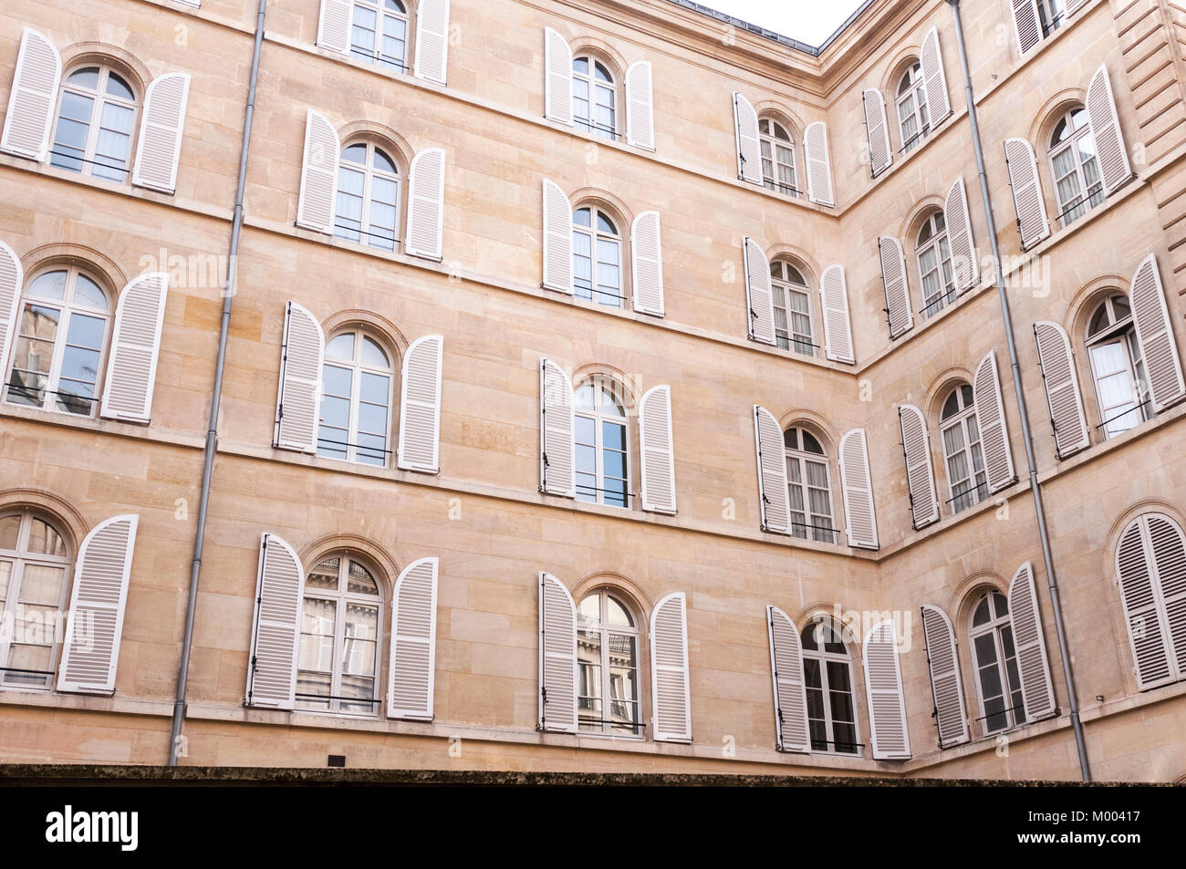 Gewölbten oberen Fenster sind durch weiße flankiert überstieg Fensterläden, ein Mietshaus in Paris Frankreich gebogen. Stockfoto