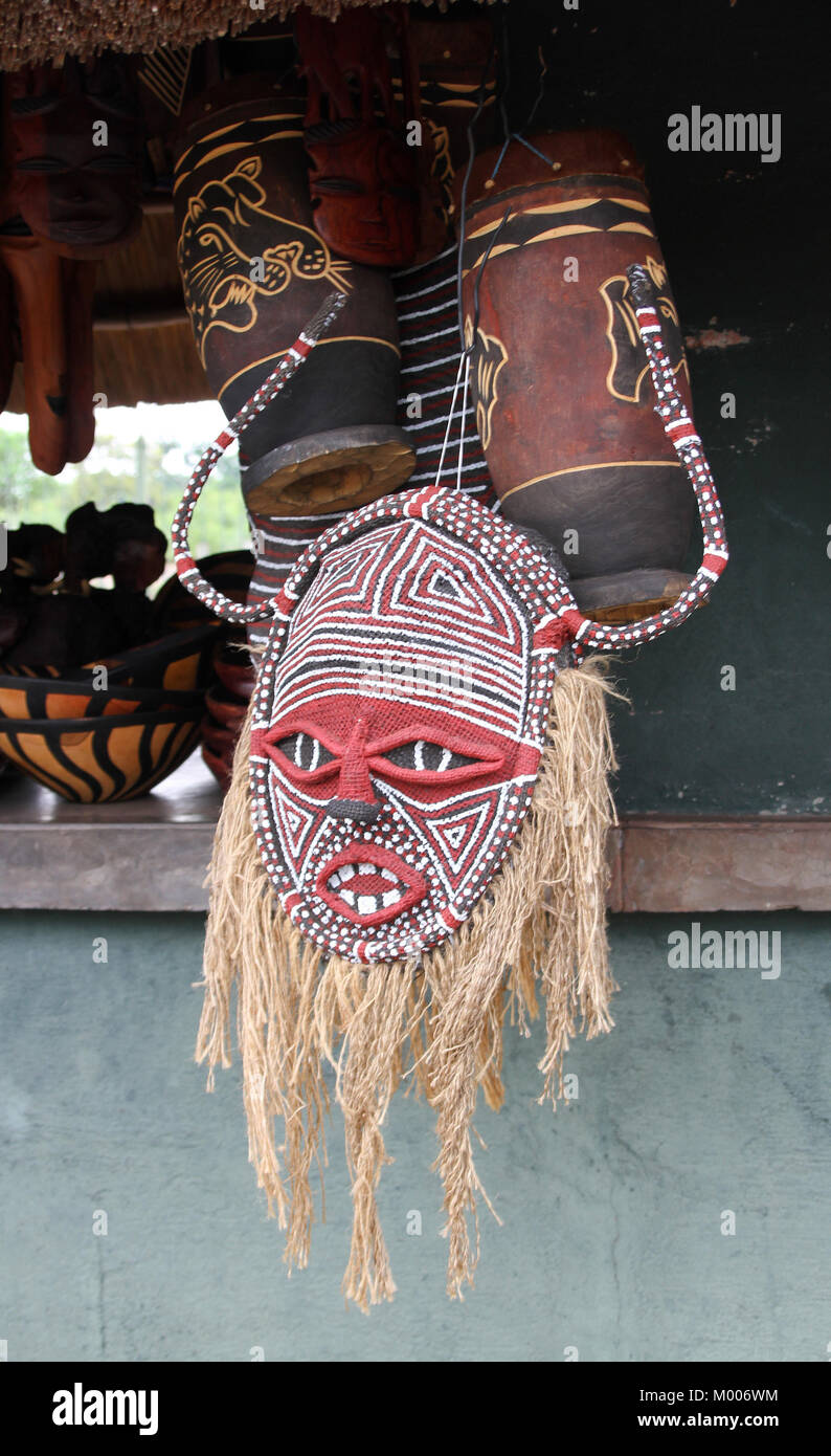 Masken, Trommeln und anderen Gütern angezeigt auf das Geschenk und Souvenir Geschäfte-Zentrum mit Strohdach, Mosi-Oa-Tunya, Viktoriafälle, Simbabwe. Stockfoto
