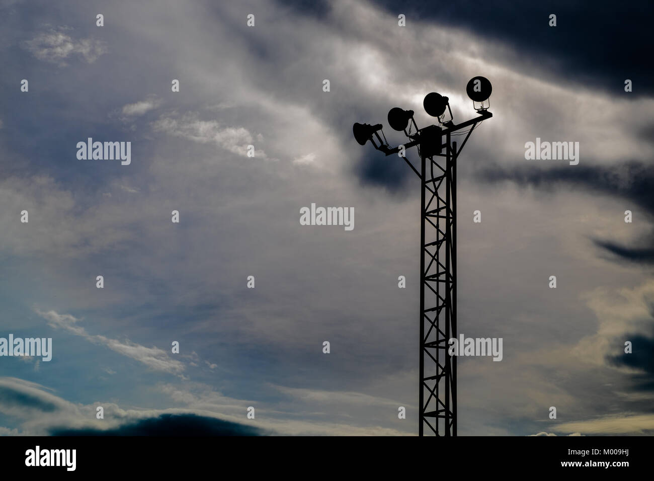 Silhouette von eigenständigen Spotlight pole wurde mit bewölkt dunkel blauen Himmel Hintergrund geschlossen, selektive konzentrieren. Stockfoto