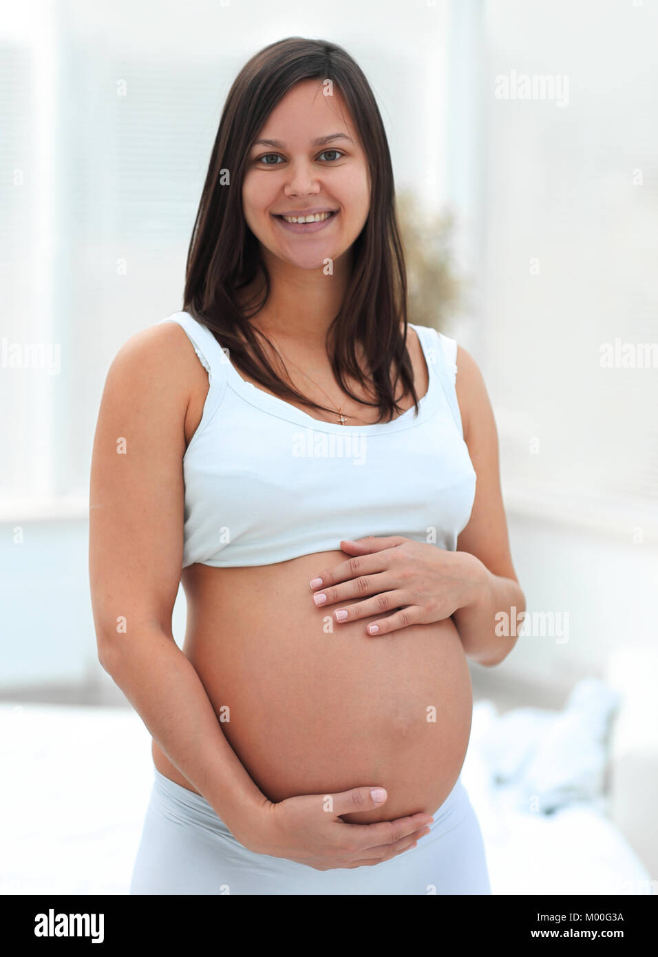 Portrait von jungen schwangeren Frau auf einem hellen Hintergrund. Stockfoto