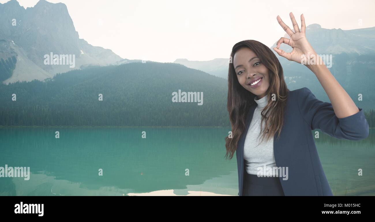 Lächelnde Frau mit ok Zeichen in den Bergen Stockfoto