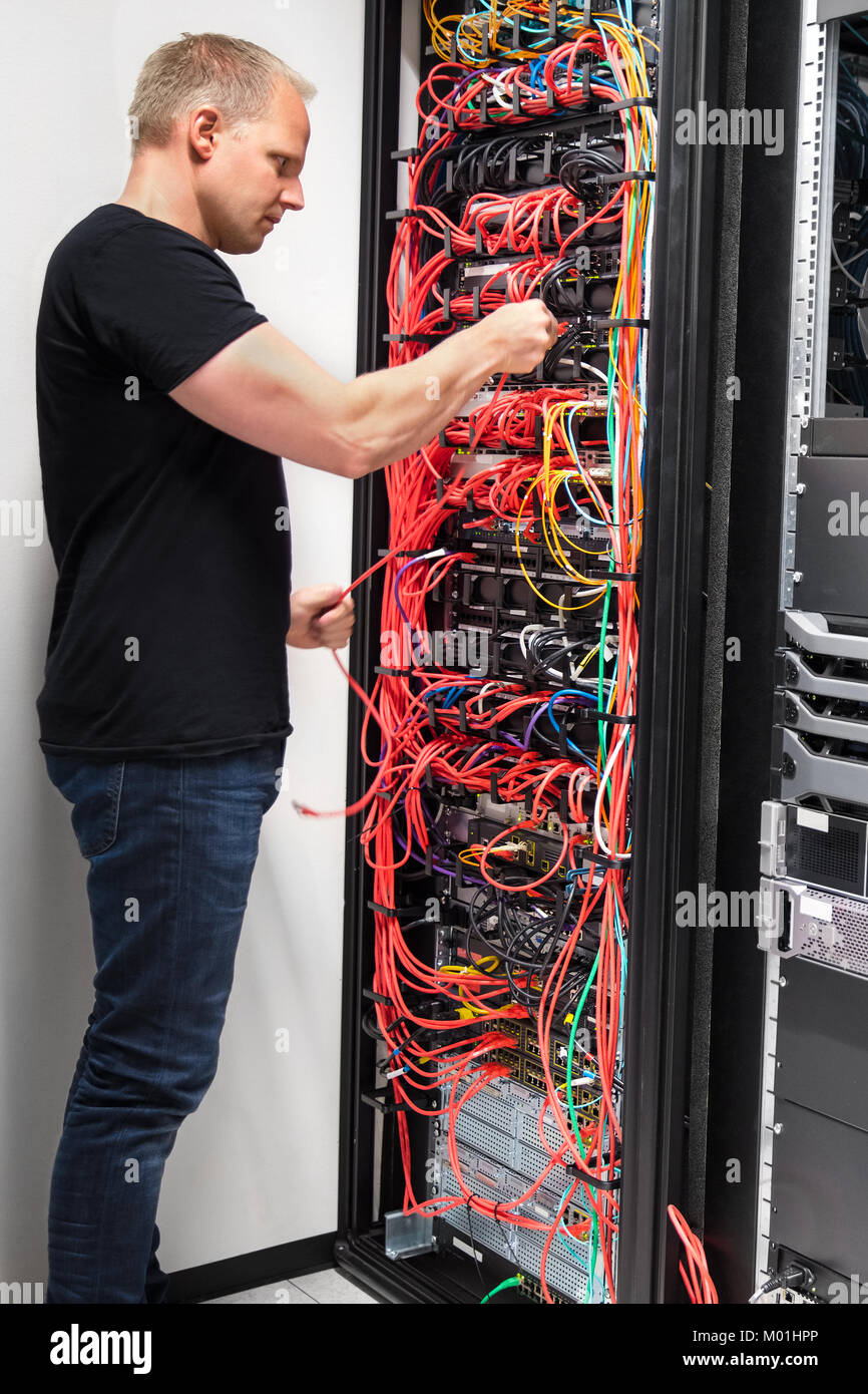 IT-Techniker mit Netzwerkkabel zu Servern Stockfoto
