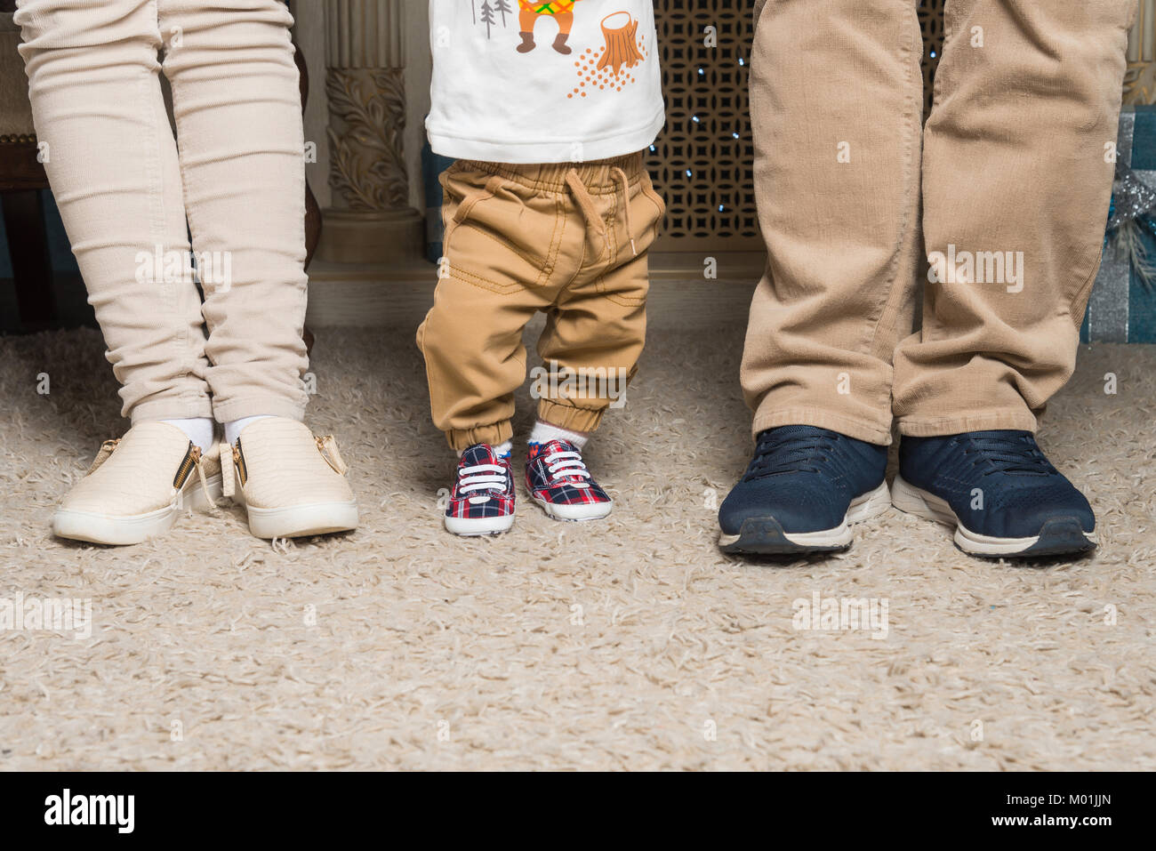 Beine von einem Ehepaar mit einem Kind in den Schuhen Stockfoto