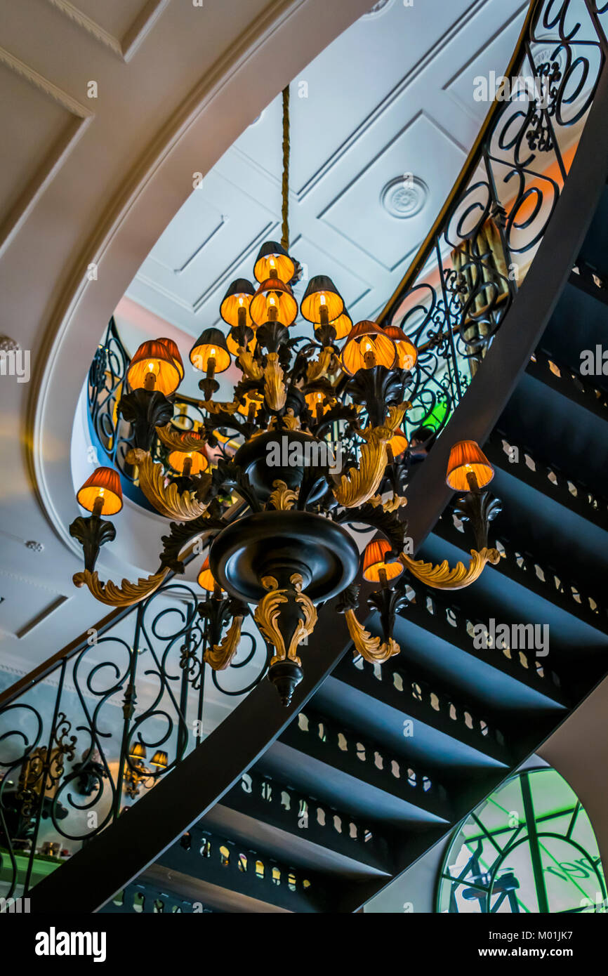 Architektur Innenraum, Kandelaber und geschwungene Treppe von unten gesehen. Gebäude Interior Detail, Wendeltreppe, Decke und Kronleuchter. Stockfoto