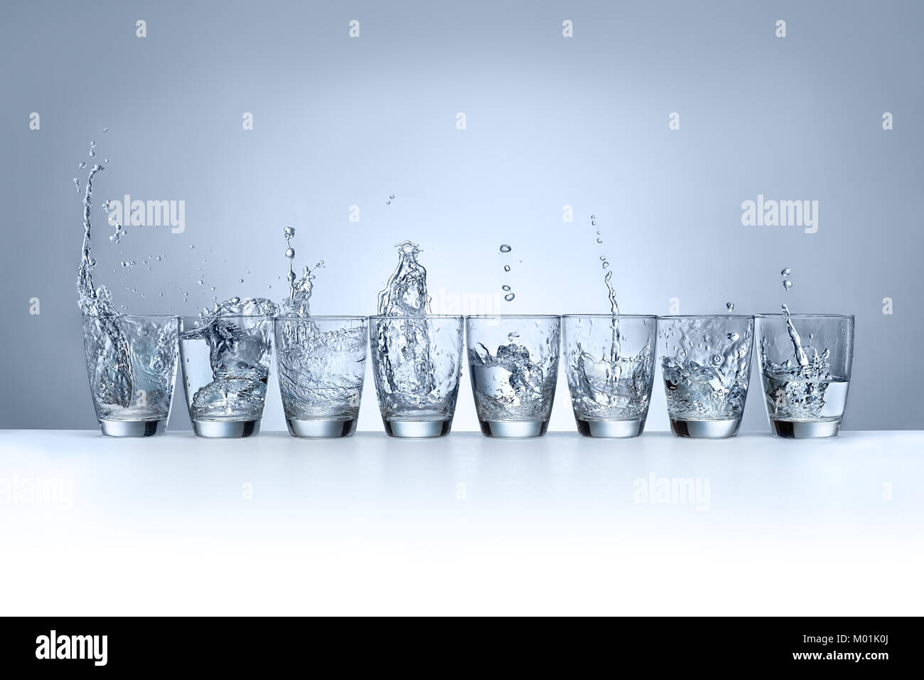 Wasser spritzt in 8 Gläser Stockfoto