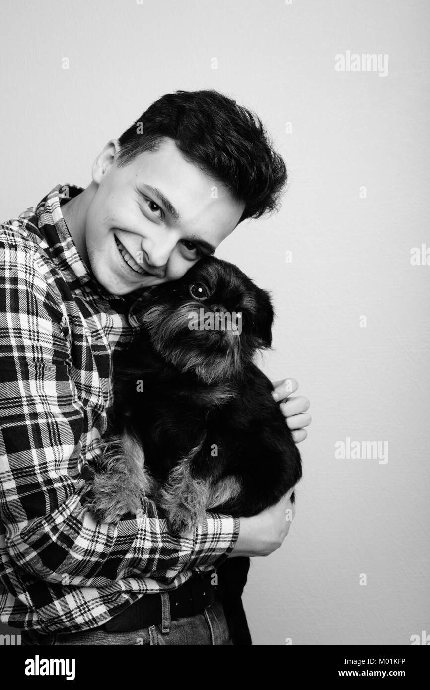 Closeup Portrait hübscher junger Mann hipster, küsste seinen guten Freund schwarzer Hund isoliert hellen Hintergrund. Positiver menschlicher Gefühle, Mimik, Stockfoto