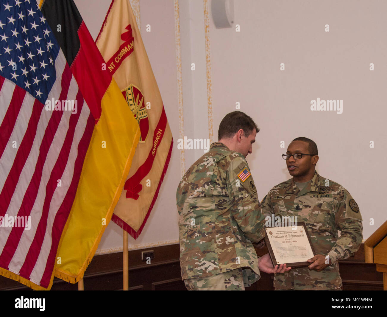 ANSBACH, Deutschland - Col. Benjamin C. Jones, U.S. Army Garrison Ansbach Commander stellt eine Bescheinigung der Anerkennung in den 1 Sgt. Alvin T. Weiß bei der Garnison jährliche Martin Luther King Jr. Beachtung, Jan 11, 2018. Das Symposium wird gemeinsam mit den 12 Combat Aviation Brigade, die jedes Jahr in die Von-Steuben Community Center auf Bismarck Kaserne. (U. S. Armee Stockfoto