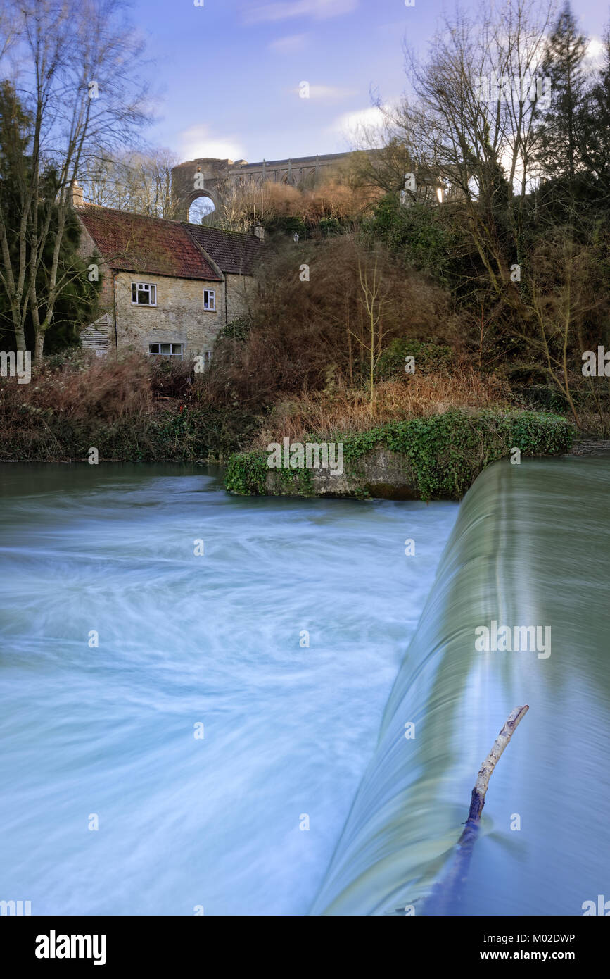 An einem windigen Tag im Januar, Wasser rauscht über den Kamm der Wehr hinter der Abtei in der Wiltshire Stadt Malmesbury. Stockfoto