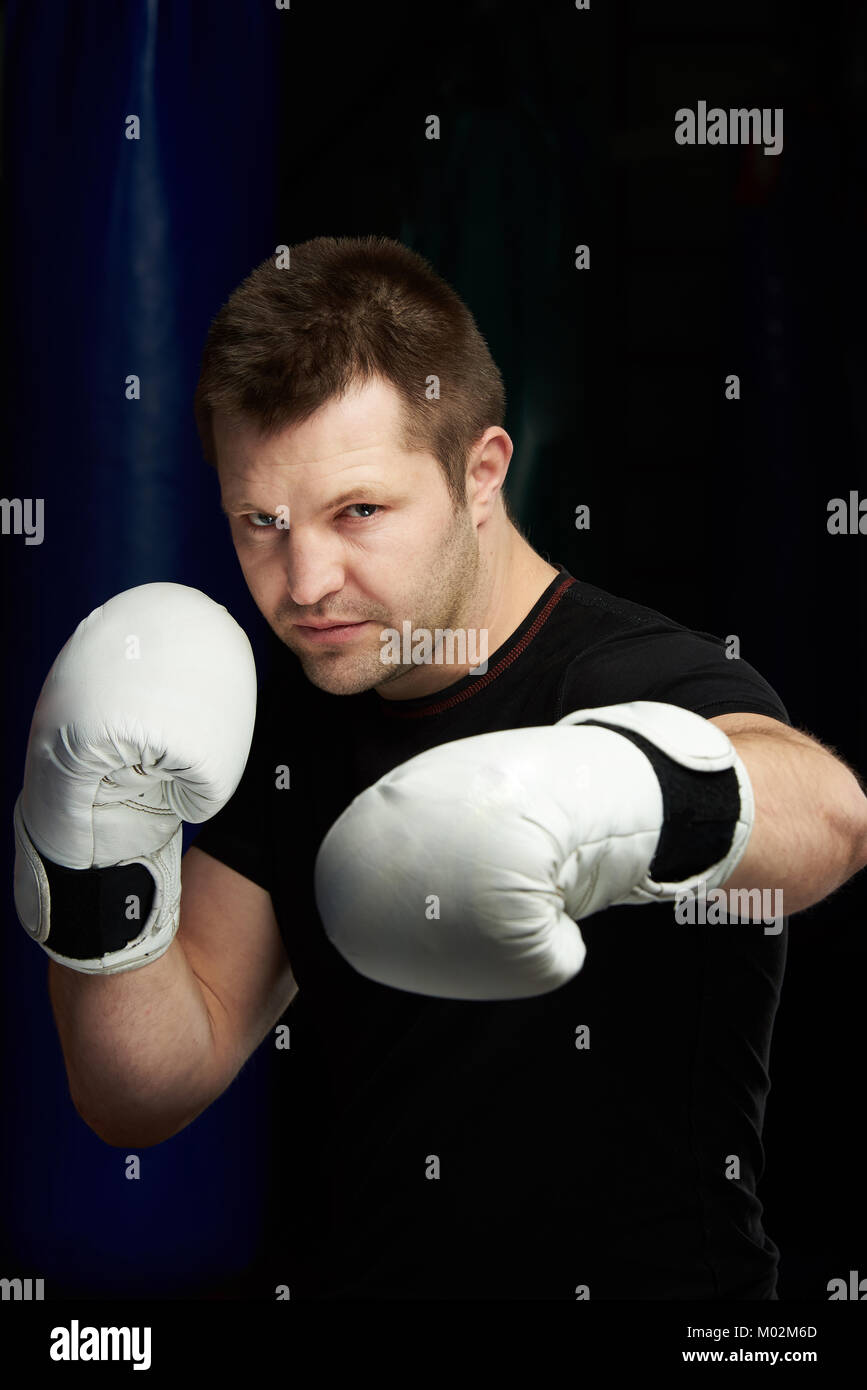 Die boxing Punch. Ein boxer Mann in weißen Handschuhen auf dunklen Turnhalle Hintergrund Stockfoto