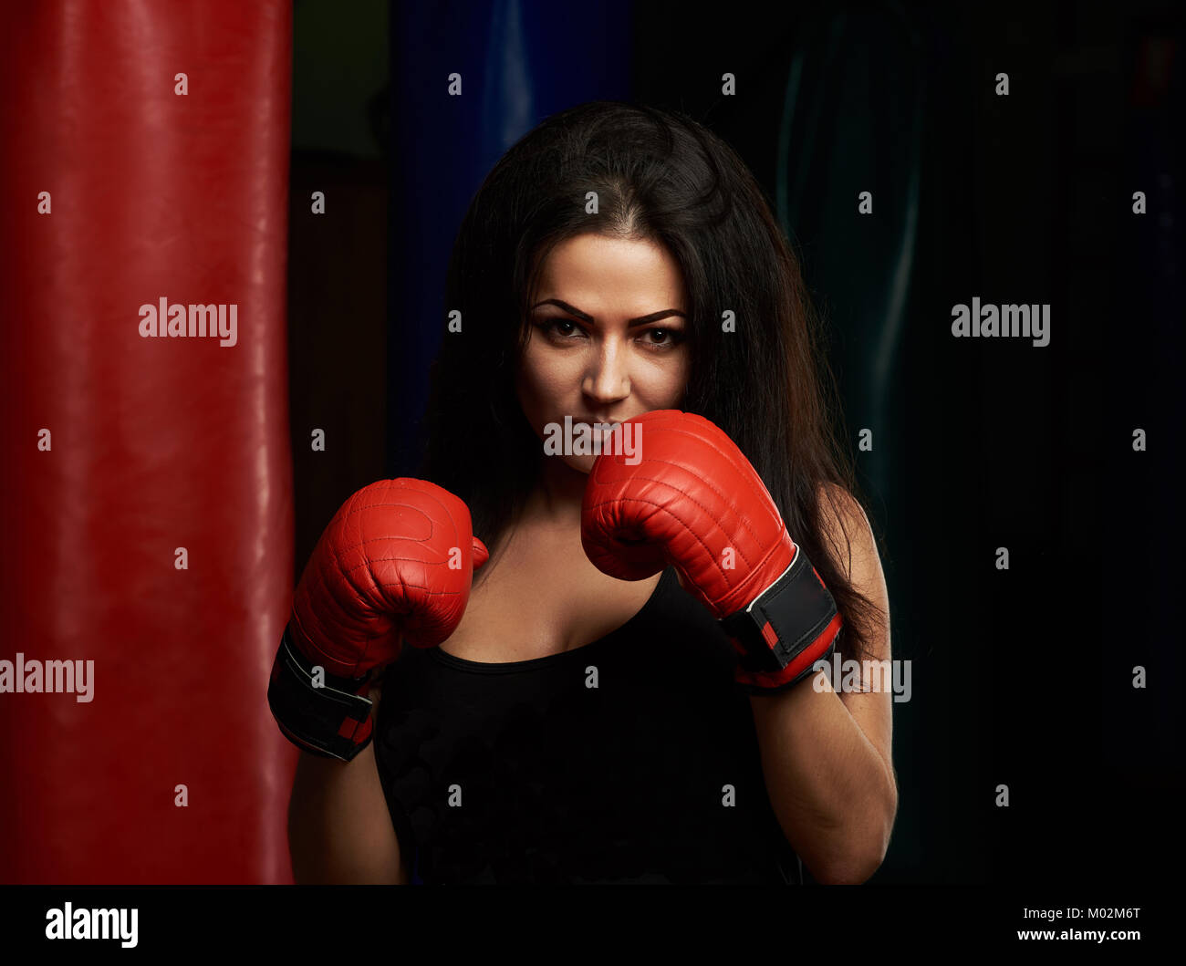 Ziemlich Boxing brunette woman holding hands up mit roten Handschuhe Stockfoto